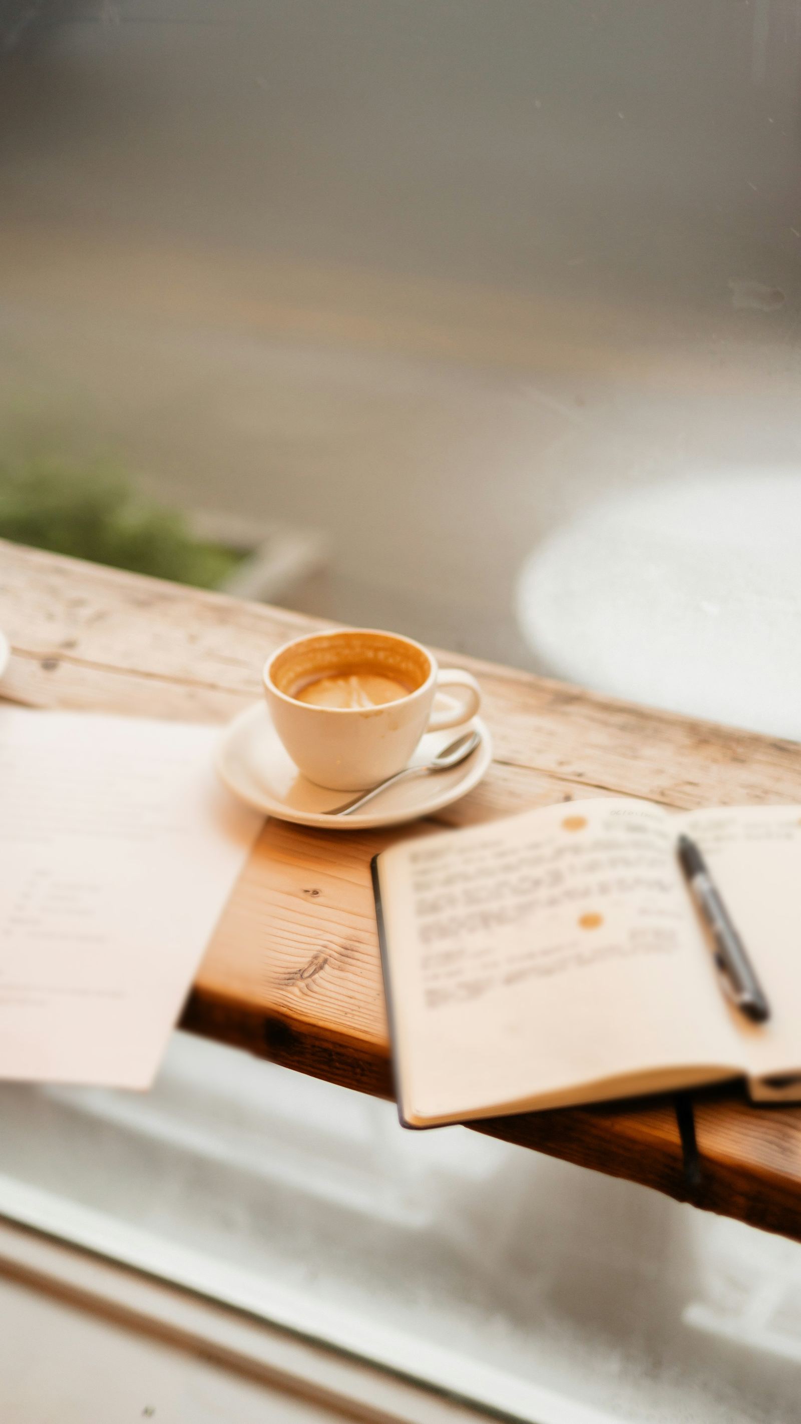 A notebook and coffee on a sunny wooden desk